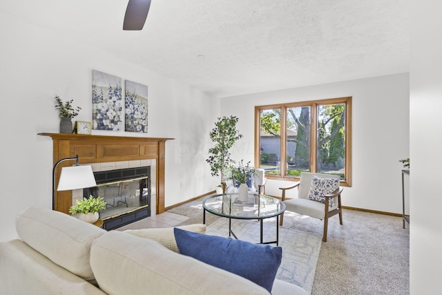 carpeted living room with a tile fireplace, a textured ceiling, and ceiling fan