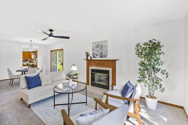 living room with ceiling fan with notable chandelier, light colored carpet, and a tile fireplace