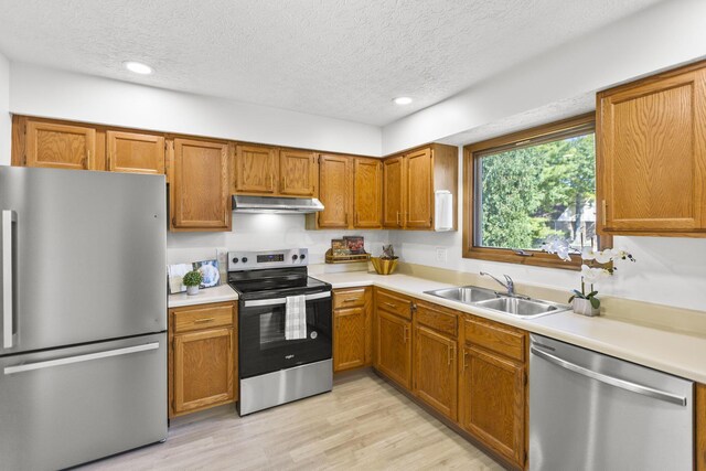 kitchen featuring sink, light hardwood / wood-style floors, a textured ceiling, and appliances with stainless steel finishes