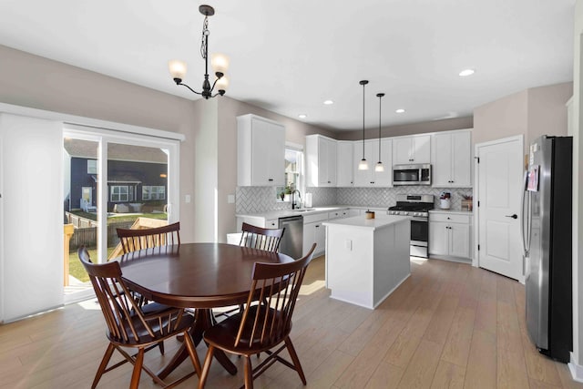 dining room with sink, an inviting chandelier, a healthy amount of sunlight, and light hardwood / wood-style flooring