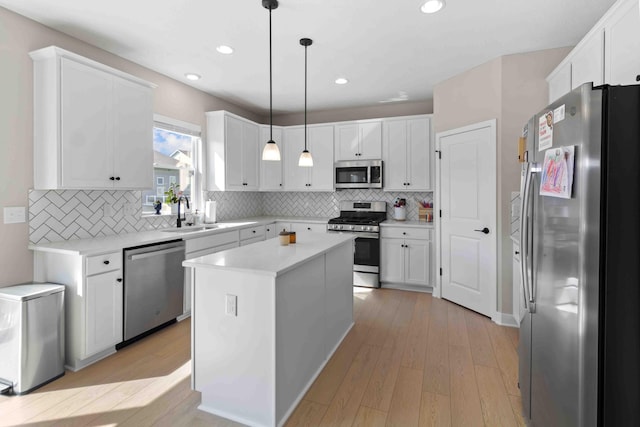 kitchen with pendant lighting, a center island, sink, light hardwood / wood-style floors, and stainless steel appliances