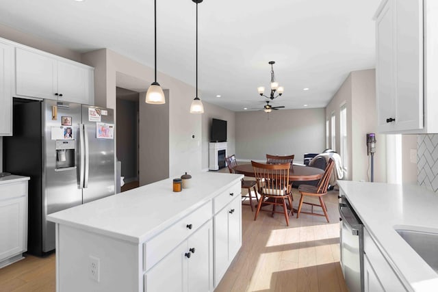 kitchen with decorative backsplash, appliances with stainless steel finishes, light wood-type flooring, and pendant lighting