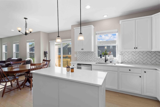 kitchen featuring sink, hanging light fixtures, plenty of natural light, and light wood-type flooring