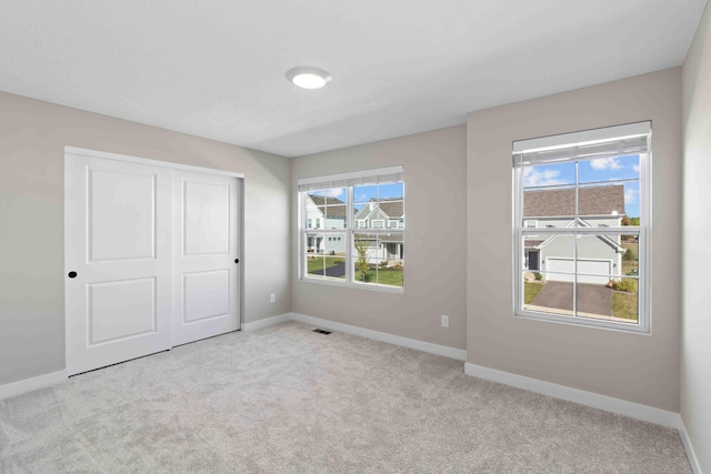 unfurnished bedroom with light colored carpet and a closet