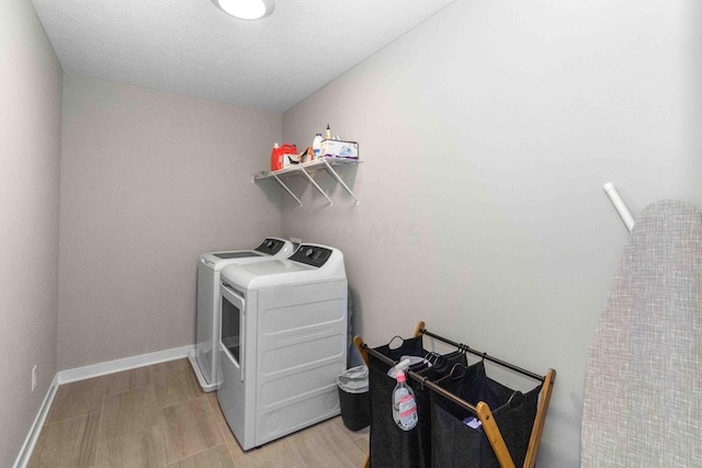 washroom with washing machine and dryer and light hardwood / wood-style floors