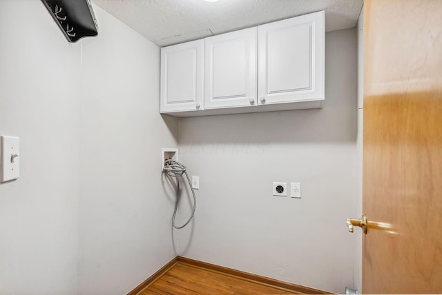 clothes washing area featuring cabinets, washer hookup, electric dryer hookup, light hardwood / wood-style floors, and a textured ceiling