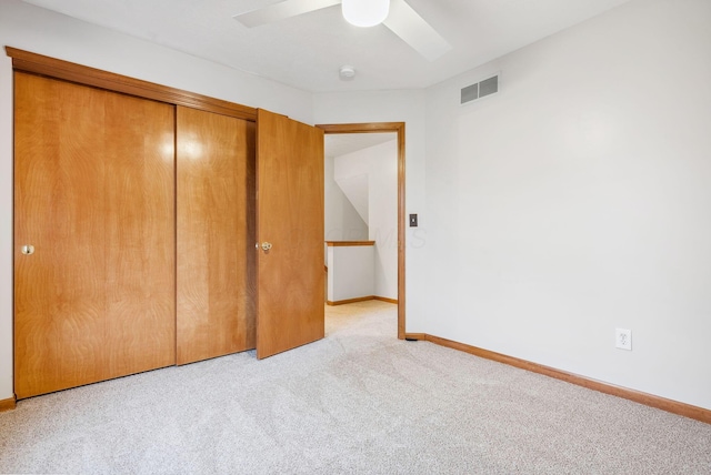 unfurnished bedroom featuring light carpet, a closet, and ceiling fan