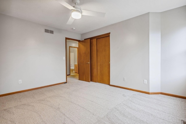 unfurnished bedroom with ceiling fan, light carpet, and a closet