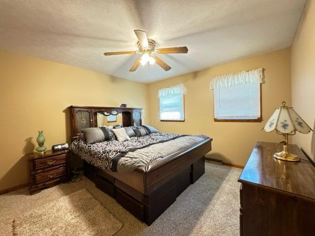 carpeted bedroom with ceiling fan and a textured ceiling