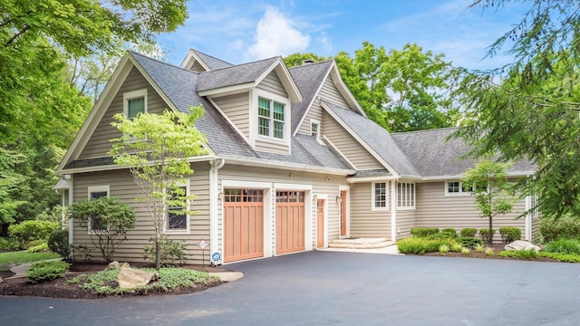 view of front facade with a garage, driveway, and roof with shingles