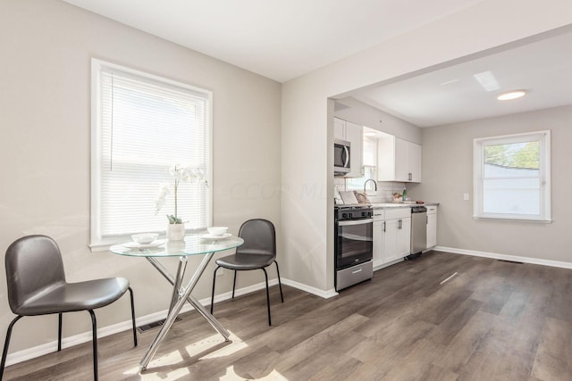 kitchen with sink, dark hardwood / wood-style floors, backsplash, white cabinets, and appliances with stainless steel finishes