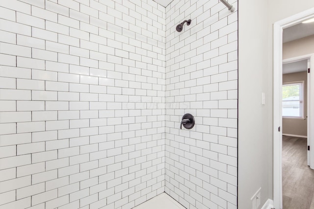 bathroom with hardwood / wood-style floors and a tile shower