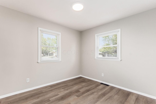 spare room with hardwood / wood-style floors and plenty of natural light