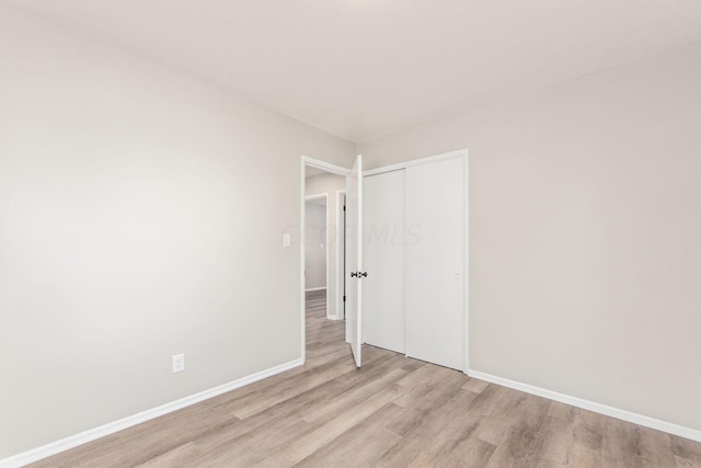 unfurnished bedroom with light wood-type flooring and a closet