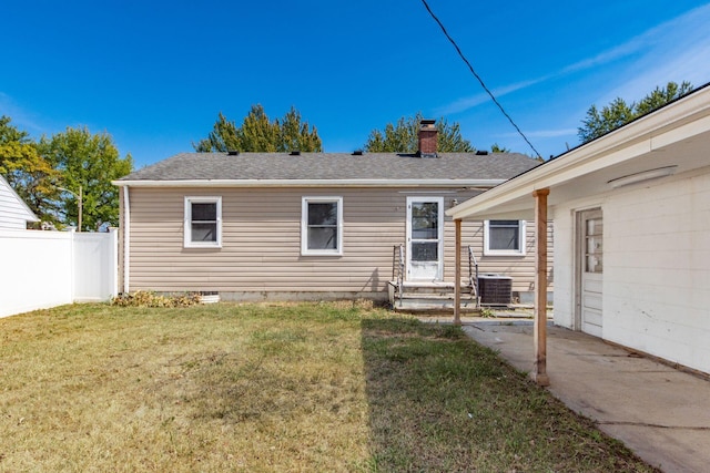 rear view of property with central air condition unit and a yard