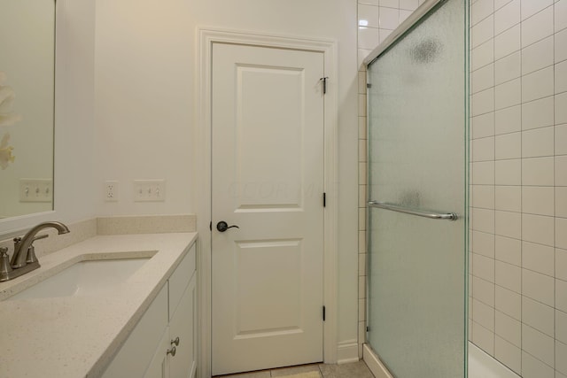 bathroom with tile patterned flooring, vanity, and walk in shower