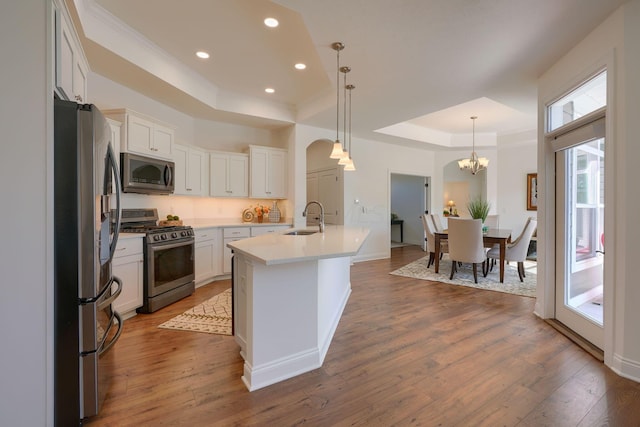 kitchen with a center island with sink, white cabinetry, hardwood / wood-style floors, and appliances with stainless steel finishes