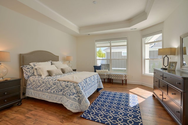 bedroom with a tray ceiling and dark wood-type flooring