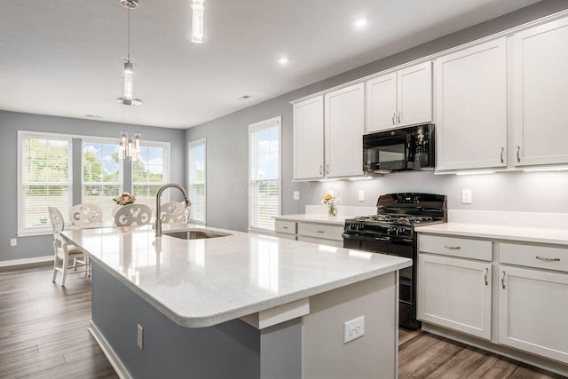 kitchen featuring sink, decorative light fixtures, a center island with sink, white cabinets, and black appliances