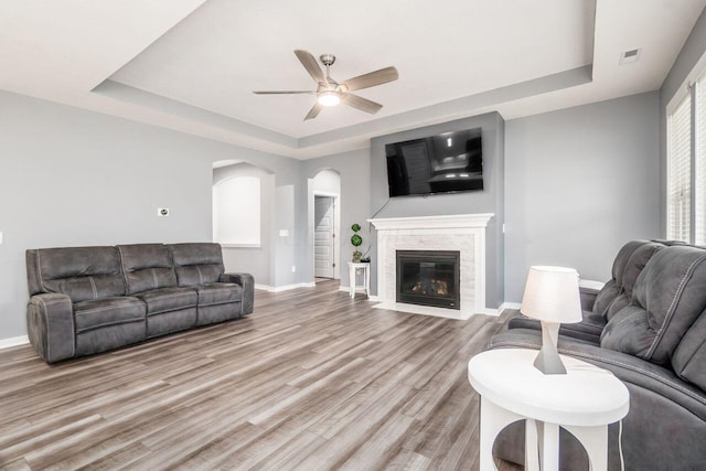 living room featuring a tray ceiling, ceiling fan, and light hardwood / wood-style flooring