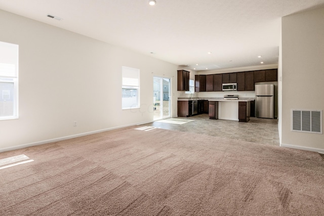 unfurnished living room featuring light carpet and sink