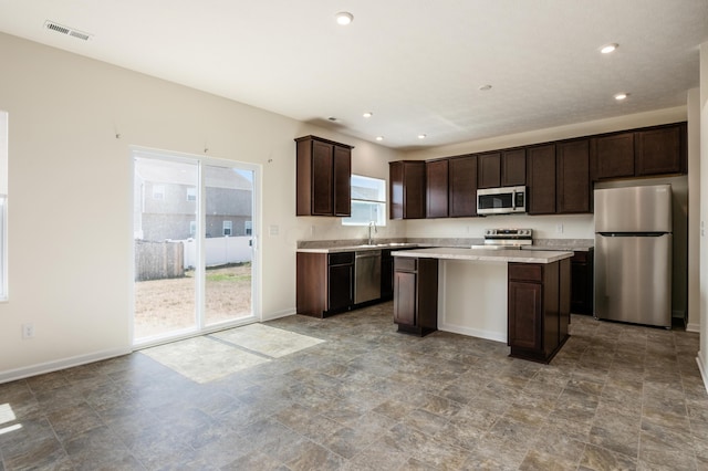 kitchen featuring a kitchen island, dark brown cabinetry, stainless steel appliances, and a wealth of natural light