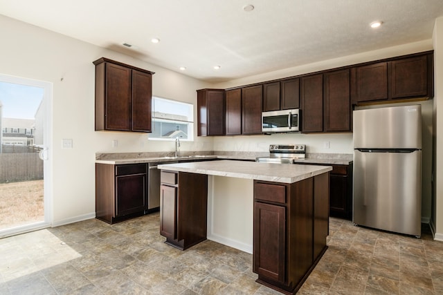 kitchen with dark brown cabinets, a kitchen island, sink, and stainless steel appliances