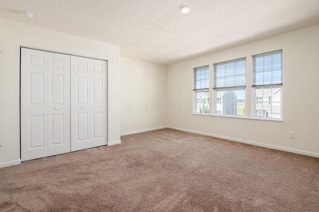 unfurnished bedroom with light carpet, a closet, and a textured ceiling