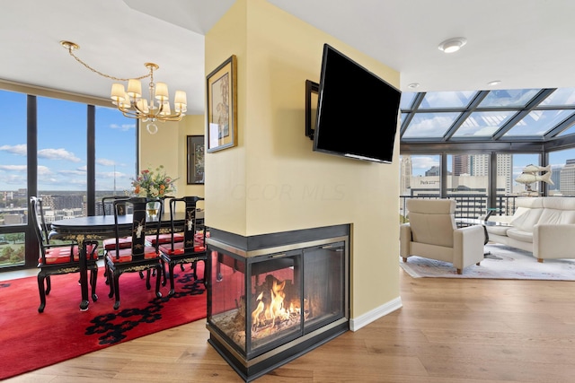 dining area featuring light wood-type flooring, a multi sided fireplace, expansive windows, and an inviting chandelier