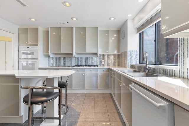 kitchen featuring white appliances, a kitchen breakfast bar, gray cabinetry, light tile patterned floors, and sink