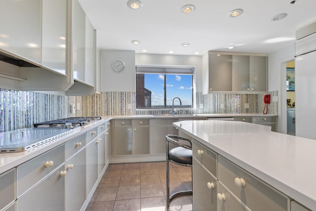 kitchen featuring sink, decorative backsplash, light tile patterned flooring, and gray cabinets