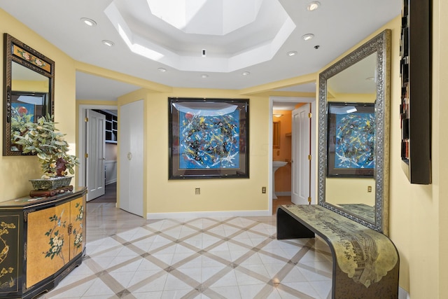 hall featuring a raised ceiling and light tile patterned floors