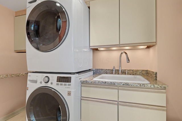 washroom featuring sink, stacked washer and clothes dryer, and cabinets