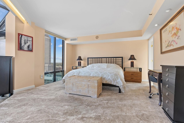 bedroom with a wall of windows and light colored carpet