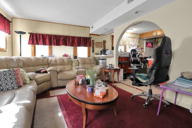 living room with carpet flooring, wood walls, and a textured ceiling