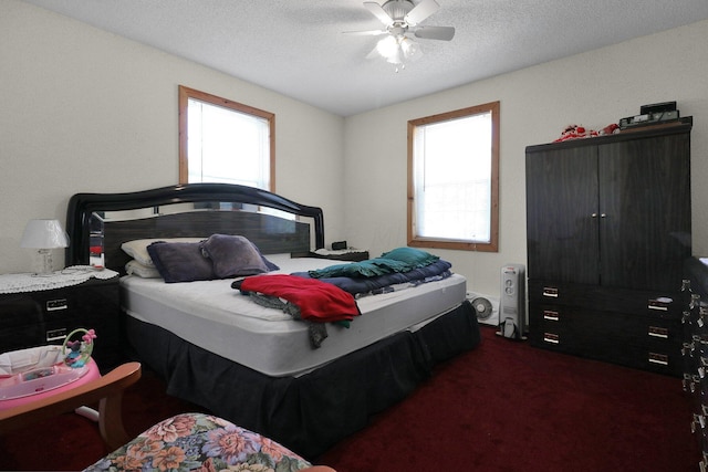 bedroom featuring ceiling fan, dark carpet, and a textured ceiling