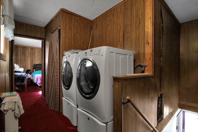 clothes washing area with a textured ceiling, separate washer and dryer, dark carpet, and wooden walls