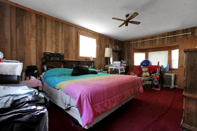 carpeted bedroom with a textured ceiling, radiator, ceiling fan, and multiple windows