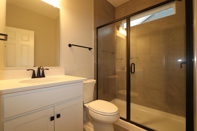 bathroom featuring toilet, vanity, and a shower with shower door