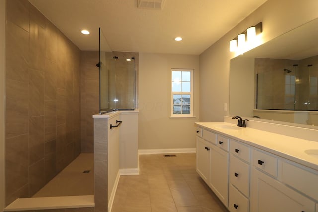 bathroom featuring tile patterned flooring, a tile shower, and vanity