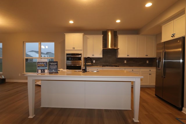 kitchen with appliances with stainless steel finishes, white cabinetry, and wall chimney exhaust hood