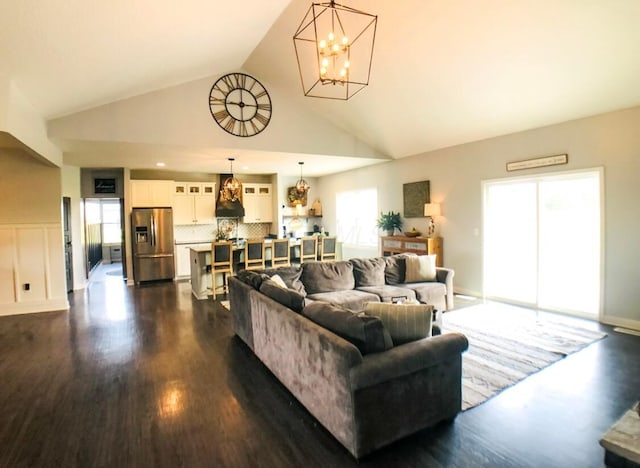 living room featuring vaulted ceiling, dark hardwood / wood-style floors, and a notable chandelier