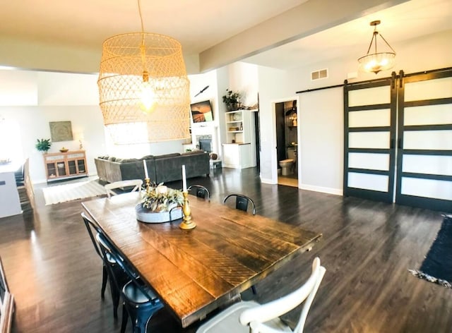 dining area featuring a barn door and dark wood-type flooring