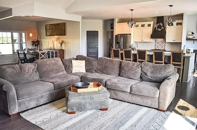 living room with dark hardwood / wood-style floors, vaulted ceiling, sink, and a chandelier