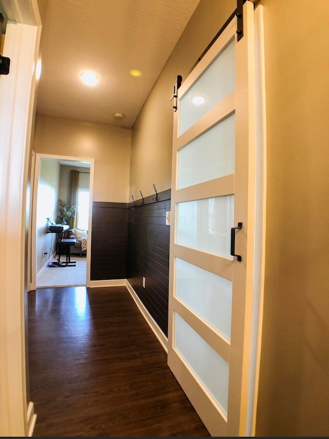 hallway with dark hardwood / wood-style flooring and a barn door