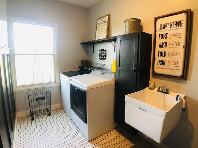 clothes washing area with washing machine and dryer, sink, and cabinets