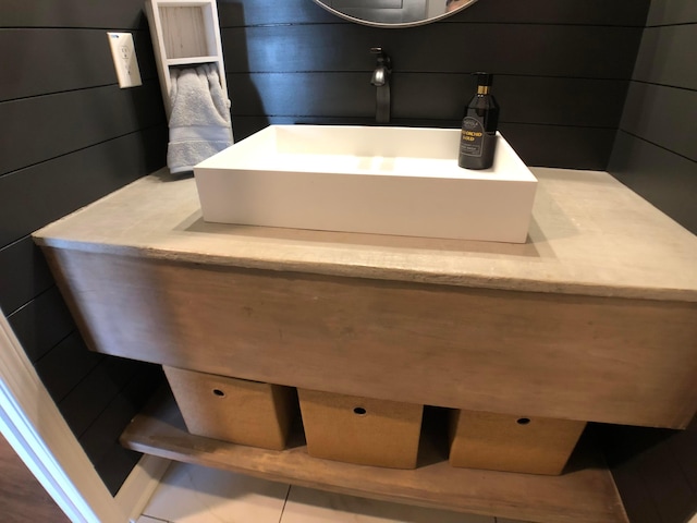 bathroom featuring tile patterned floors, wood walls, and sink