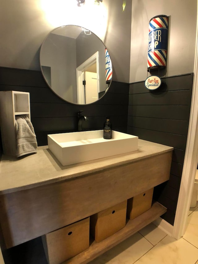 bathroom with tile patterned floors, wood walls, and sink