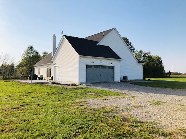 view of side of property with cooling unit, a garage, and a yard