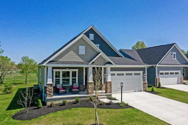 craftsman inspired home with covered porch, a garage, and a front lawn